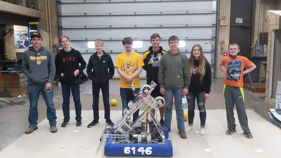 Eight robotics members stand behind the robot.